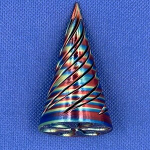 May include: A conical object featuring a metallic finish with a swirling, iridescent pattern of red, blue, and gold colors. The surface has deep, diagonal grooves that spiral toward the pointed top, and the base has a star-shaped cutout.