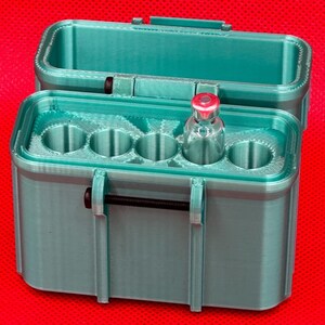 May include: A teal 3D-printed storage case with a hinged lid and a black metal latch mechanism. The interior features five circular slots designed for vials, with one clear glass vial containing a red cap inserted into the second slot.