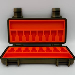 May include: An olive green rectangular hard-shell storage case with a hinged lid, featuring a bright orange interior foam insert with eight molded slots on the top and bottom sections for organizing small items securely.