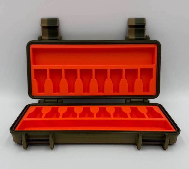 May include: An olive green rectangular hard-shell storage case with a hinged lid, featuring a bright orange interior foam insert with eight molded slots on the top and bottom sections for organizing small items securely.