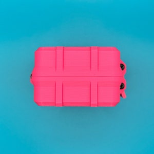 Puede incluir: Un estuche de almacenamiento rectangular de color rosa ne&oacute;n brillante con un exterior acanalado de estilo industrial. El estuche presenta dos tornillos negros visibles en el mecanismo de bisagra lateral y un cierre de pestillo seguro.