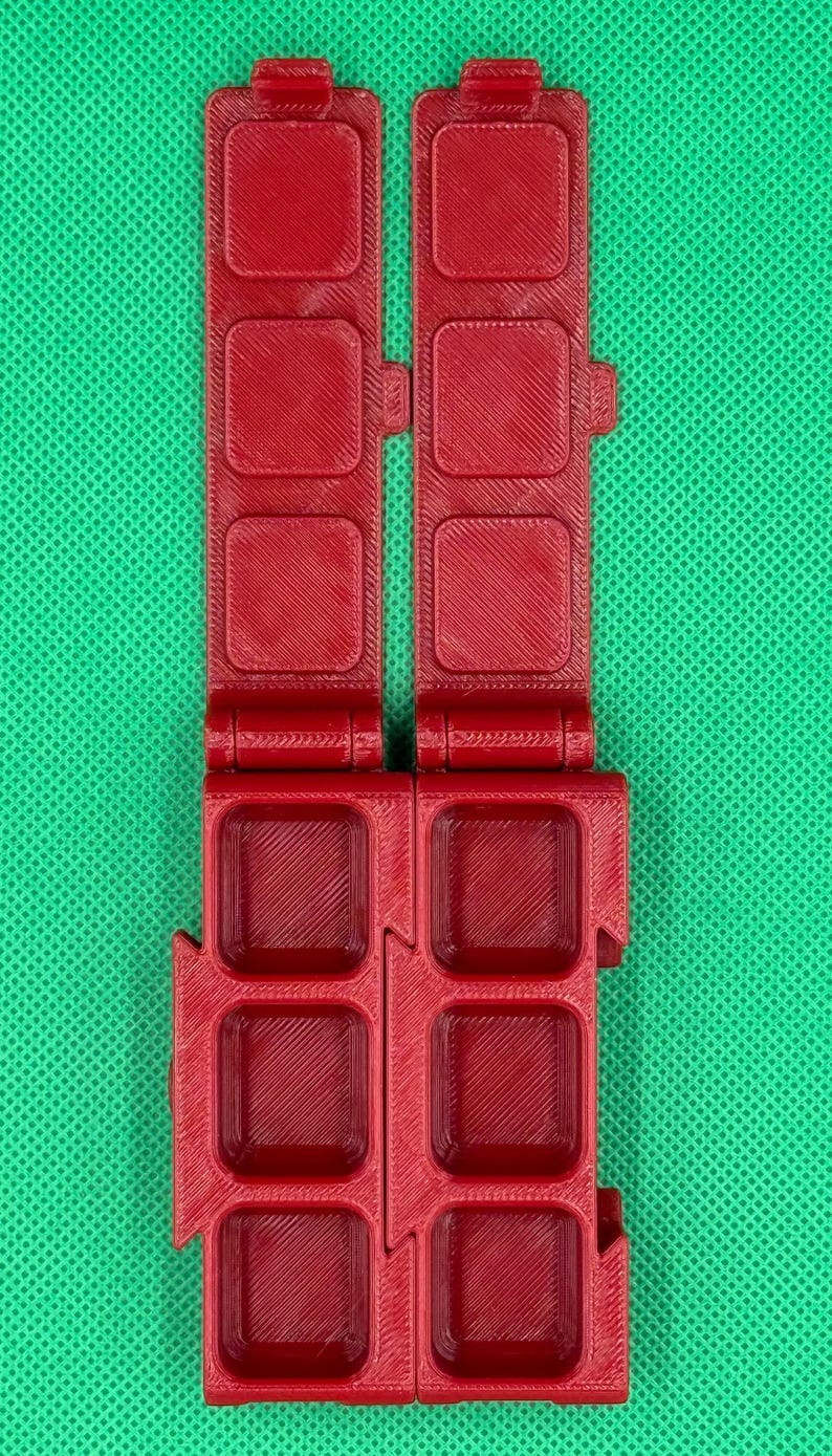 Puede incluir: Una caja de almacenamiento de pl&aacute;stico roja con una tapa con bisagras. La caja tiene ocho compartimentos, cada uno con forma cuadrada.