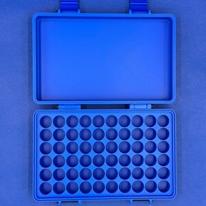 K&ouml;nnte beinhalten: Ein leuchtend blauer, rechteckiger Aufbewahrungskoffer mit offenem Deckel. Der Innenboden verf&uuml;gt &uuml;ber ein Raster aus f&uuml;nfzig kreisf&ouml;rmigen Vertiefungen in f&uuml;nf Reihen zu je zehn, um kleine Gegenst&auml;nde sicher in der Hartschale zu halten.