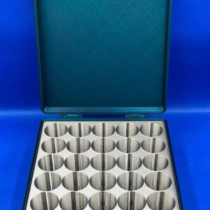 May include: A teal green plastic storage case with a hinged lid. The case has 24 round compartments for storing small items.