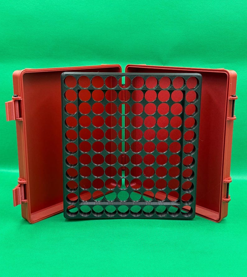May include: A red plastic storage case with a black grid insert. The case is open and the grid insert is visible. The grid insert has many circular holes.