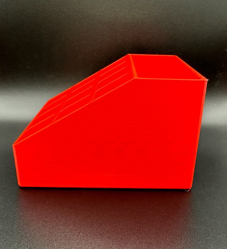 May include: A bright red plastic organizer with multiple compartments. The organizer is angled and has a rectangular shape.