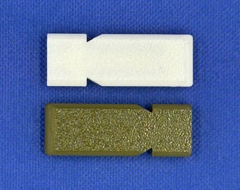 May include: Two rectangular plastic components with a textured surface and a notched side. One component is solid white, and the other is olive green. Both items feature a flat, elongated shape with a distinct indentation on one side.