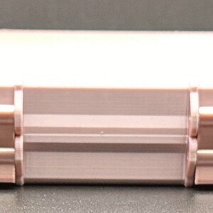 May include: A rectangular, light pink storage case featuring a smooth, solid-colored exterior. The case is constructed with two prominent hinges on the front side, each secured with small, dark-colored pins, providing a functional closure mechanism.