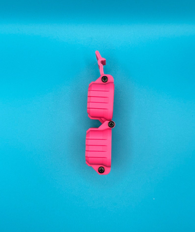 May include: A bright pink, hinged, rectangular plastic case with a ribbed texture on the exterior. The case features three small black screws securing the hinges and closure mechanism, shown in a vertical orientation against a blue background.
