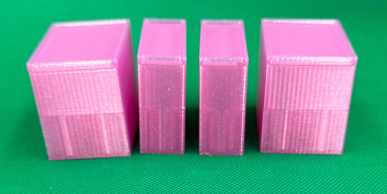 May include: Four rectangular, translucent pink plastic containers with lids. The two outer containers are wider than the two inner containers. Each container features a vertical ribbed texture on the sides and a smooth, flat top surface.