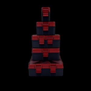 May include: A stack of five rectangular storage cases arranged from smallest at the top to largest at the bottom. Each case is dark blue with a red lid and features two red locking latches on the front for secure closure.