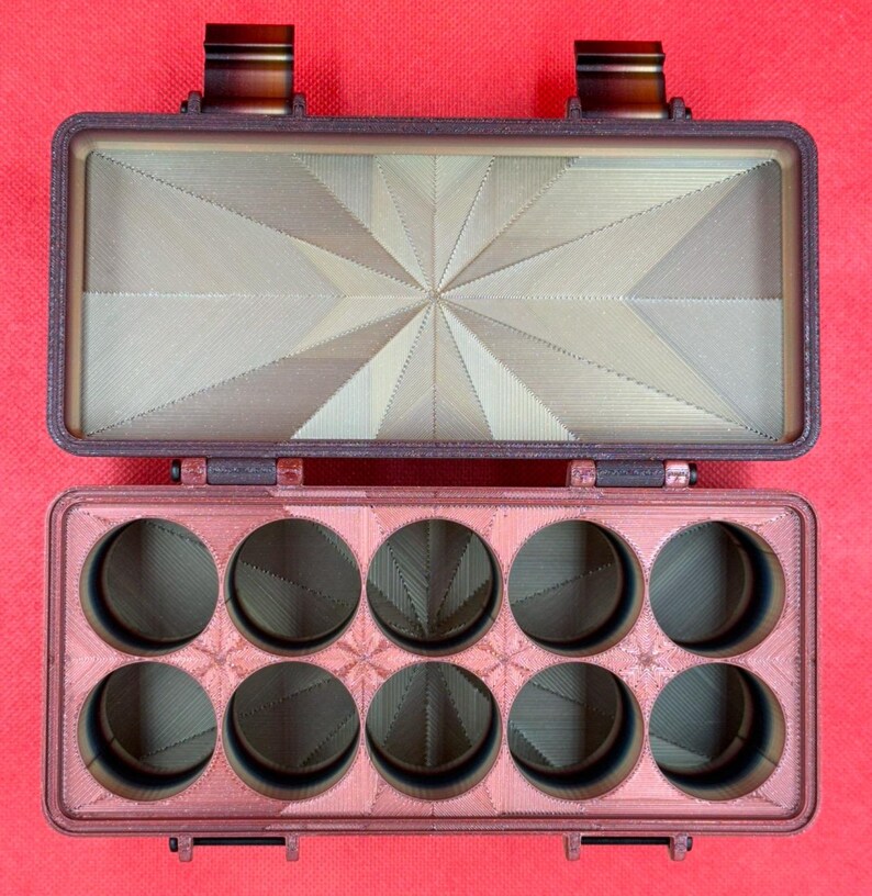 Puede incluir: Un estuche de almacenamiento rectangular de color marr&oacute;n oscuro impreso en 3D con tapa abatible. La base interior tiene diez compartimentos circulares en dos filas de cinco, y el interior de la tapa muestra un patr&oacute;n geom&eacute;trico de estrella.