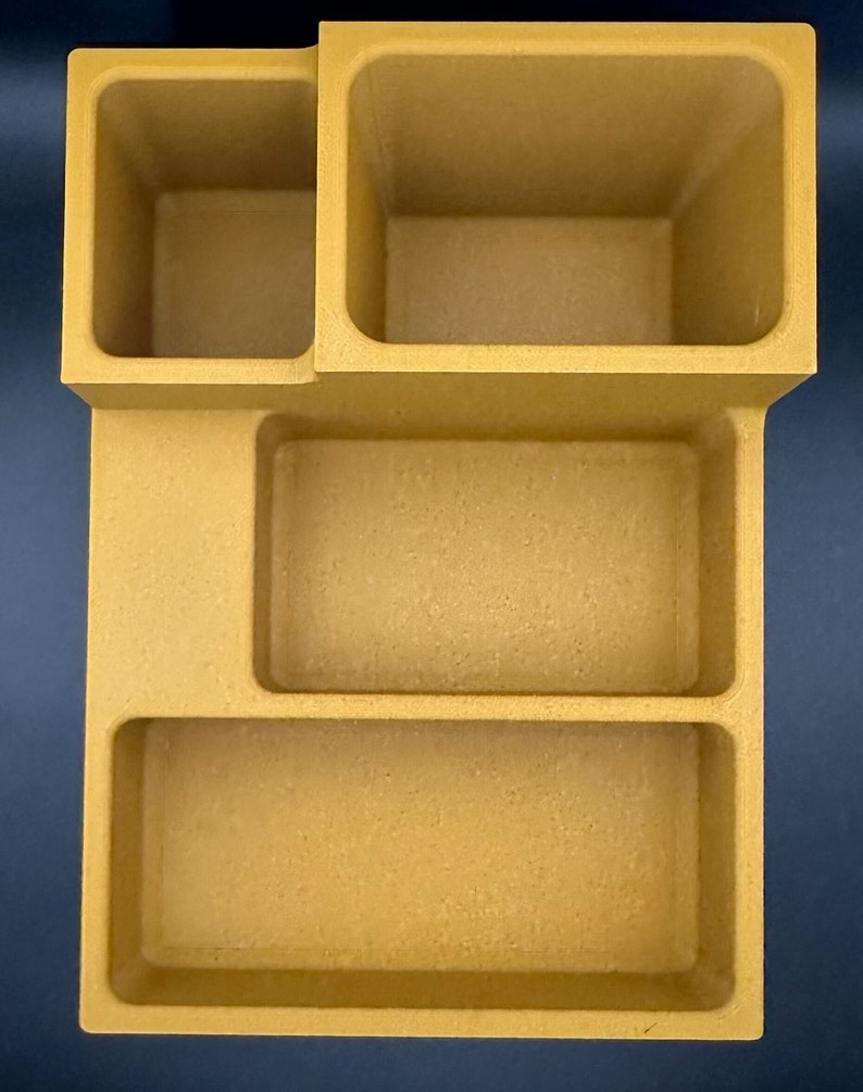 Op de afbeelding: Een beige bureaustoel met vier vakken. De organizer heeft een vierkante vorm met een rechthoekig vak aan de onderkant en drie kleinere rechthoekige vakken aan de bovenkant.