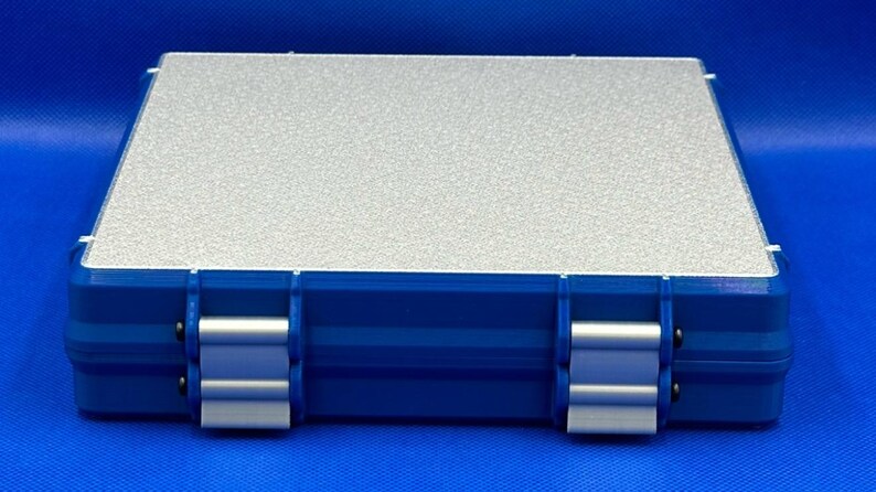 K&ouml;nnte beinhalten: Eine blaue Plastik-Aufbewahrungsbox mit einem silbernen Deckel. Die Box hat zwei Verschl&uuml;sse an jeder Seite und eine strukturierte Oberfl&auml;che.