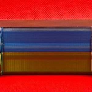 May include: A blue and gold rectangular storage case with two latches on each side. The case has a textured surface and is made of durable plastic.