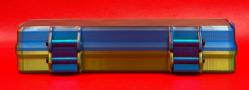 May include: A blue and gold rectangular storage case with two latches on each side. The case has a textured surface and is made of durable plastic.