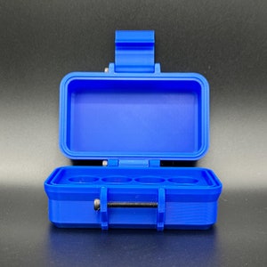 May include: A bright blue rectangular storage case with an open lid. The interior base features four circular indentations for holding small items. A single black metal screw acts as a latch mechanism on the front of the blue plastic container.