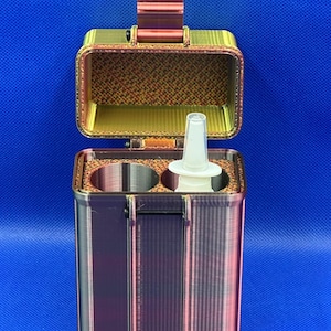 May include: A red and gold 3D printed case with a hinged lid, designed to hold two nasal spray bottles. The case has a textured surface and a small white nasal spray bottle is visible inside.