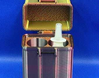 Könnte beinhalten: Ein rechteckiges Aufbewahrungsgehäuse in Metallic-Tönen mit Klappdeckel, das einen Farbverlauf aus Kupfer-, Gold- und Bronzetönen aufweist. Das Innere enthält zwei kreisförmige Fächer, von denen eines eine kleine, weiße, konische Kunststoffdüse enthält.