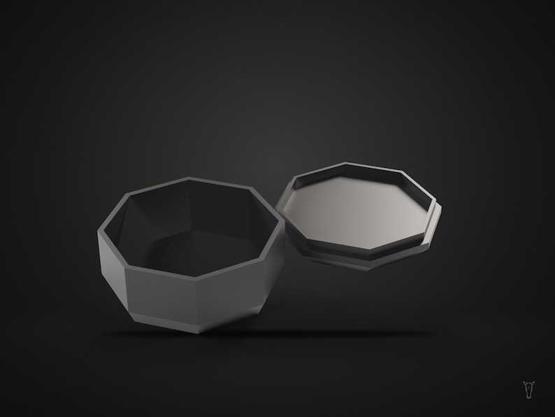 May include: A matte dark gray octagonal container with a matching lid positioned beside it. The container features a hollow interior and a flat base, while the lid is flat with a raised edge that fits the octagonal opening of the base.