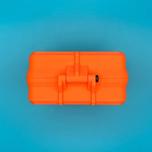 May include: A bright orange rectangular hard-shell storage case featuring a central latch mechanism and a small black circular pin detail on the side, presented in a closed position with a clean, uniform exterior surface design.