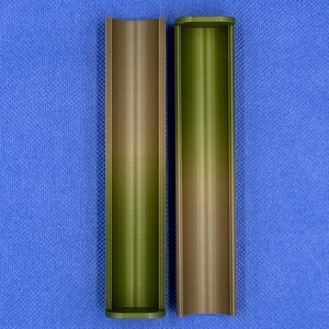 May include: Two empty, cylindrical containers made of a brown and green plastic material. The containers are open at one end and closed at the other. They are both standing upright on a blue surface.