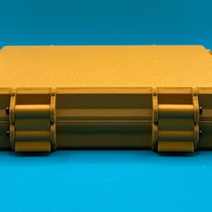 May include: A rectangular, mustard-yellow storage case with a textured, matte finish. The case features a hinged design with two prominent front latches secured by small black pins, providing a sturdy and secure closure for the container.