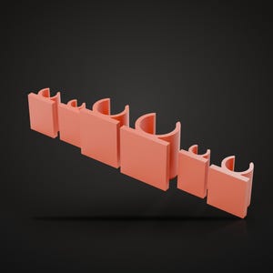 Puede incluir: Un organizador de pared de plástico color salmón que presenta una serie de paneles planos cuadrados alternados con clips semicirculares diseñados para sujetar objetos cilíndricos, dispuestos en una fila horizontal lineal.