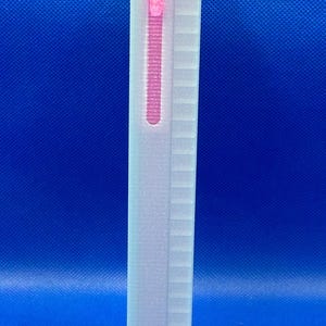 May include: A rectangular, off-white, semi-translucent electronic device with a textured, ribbed side panel. A vertical, narrow, glowing pink light indicator is embedded near the top edge of the device, showing an active status.