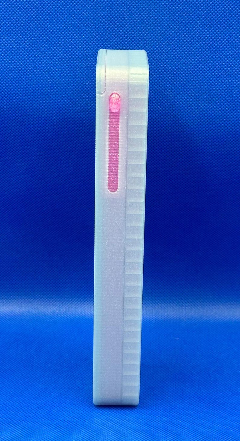 May include: A rectangular, off-white, semi-translucent electronic device with a textured, ribbed side panel. A vertical, narrow, glowing pink light indicator is embedded near the top edge of the device, showing an active status.