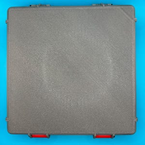 May include: A gray plastic storage box with a textured surface and red accents on the edges.