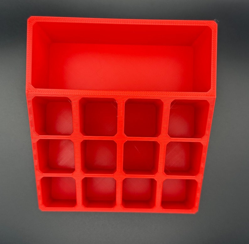 May include: A red plastic organizer with 12 compartments. The organizer has a rectangular shape and is made of a smooth, glossy plastic.