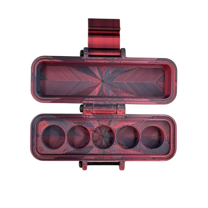 Puede incluir: Un estuche de almacenamiento rectangular con bisagra y acabado jaspeado en rojo y negro. El interior de la base contiene cinco compartimentos circulares, mientras que la tapa superior es hueca con un patr&oacute;n geom&eacute;trico texturizado.
