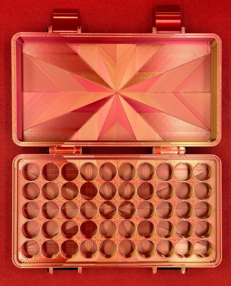 May include: A red plastic storage box with a hinged lid. The box has 36 round compartments for storing small items.