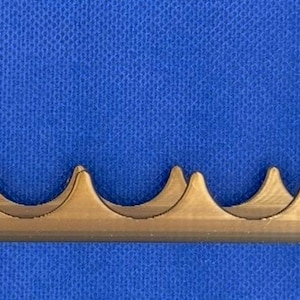 K&ouml;nnte beinhalten: Ein goldfarbener Metallst&auml;nder mit einer Reihe von geschwungenen Vertiefungen, die f&uuml;r die Aufnahme mehrerer Gegenst&auml;nde ausgelegt sind. Der St&auml;nder hat an jedem Ende zwei vertikale Pfosten.