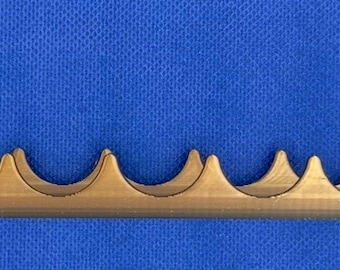 May include: A gold-colored metal stand with a series of curved indentations designed to hold multiple items. The stand has two vertical posts on each end.