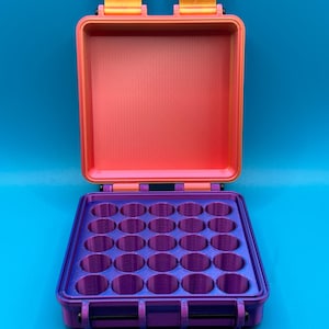 May include: A rectangular storage case with an open lid, featuring a bright orange interior and exterior frame. The base contains a purple insert with twenty-five circular compartments arranged in a five-by-five grid for organized storage.