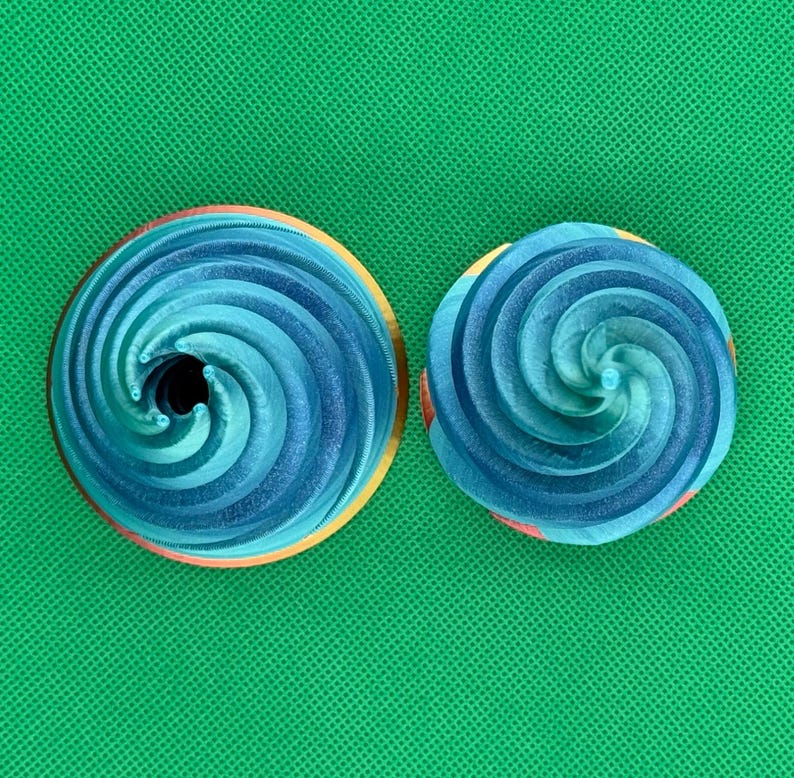 May include: Two blue and white swirl cake toppers. The cake toppers are made of a smooth, shiny material and have a spiral design.