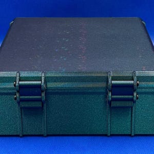 May include: A dark green plastic storage case with two black latches. The case has a textured surface and a iridescent finish.