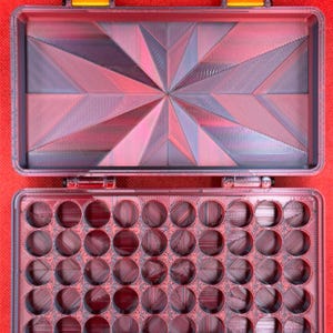May include: A red plastic storage case with a geometric pattern on the lid and 36 round compartments in the bottom.