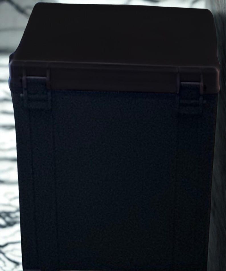 May include: A black rectangular box with a hinged lid. The box has a textured surface and a darker trim around the lid. The box appears to be made of a durable material, suitable for storage or transport.