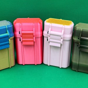 Puede incluir: Cuatro cajas de almacenamiento rectangulares con tapas abatibles y cierres de seguridad. La primera tiene un degradado azul y amarillo, la segunda es rosa brillante, la tercera es rosa pastel claro con tapa amarilla y la cuarta es verde oliva oscuro.