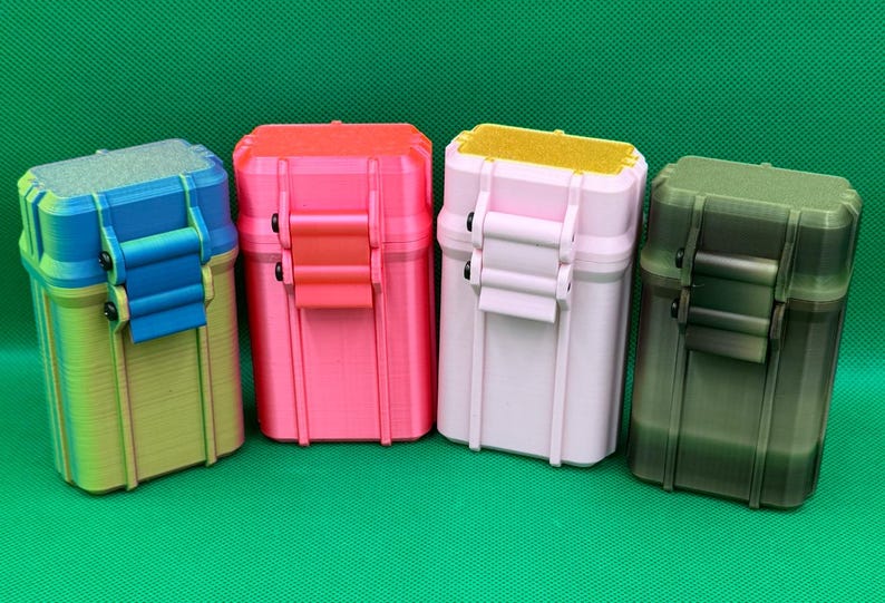 Puede incluir: Cuatro cajas de almacenamiento rectangulares con tapas abatibles y cierres de seguridad. La primera tiene un degradado azul y amarillo, la segunda es rosa brillante, la tercera es rosa pastel claro con tapa amarilla y la cuarta es verde oliva oscuro.