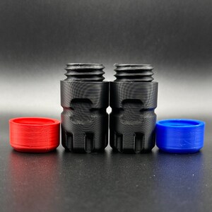 May include: Two black cylindrical threaded adapters with textured sides, accompanied by one separate red circular cap and one separate blue circular cap, all featuring a matte finish and visible 3D printed layer lines.