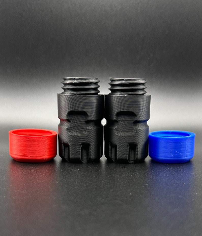 May include: Two black cylindrical threaded adapters with textured sides, accompanied by one separate red circular cap and one separate blue circular cap, all featuring a matte finish and visible 3D printed layer lines.