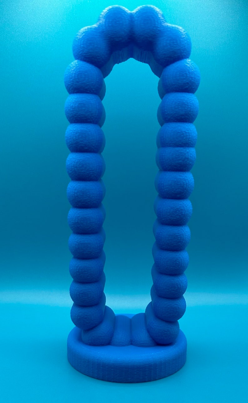 May include: A blue 3D printed archway sculpture made of a series of connected spheres. The archway is standing on a blue base.
