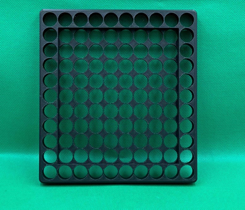 May include: Black plastic storage tray with a grid of circular holes. The tray is designed to hold small items, such as coins, beads, or buttons.