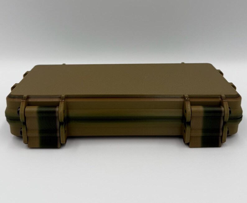 May include: A rectangular, tan-colored hard-shell storage case with a smooth, flat top surface. The case features two prominent, dark-colored locking latches on the front edge, designed to secure the lid firmly to the base of the container.