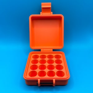 May include: A bright orange, square, hard-shell storage case with a hinged lid. The interior base features a grid of sixteen circular, recessed compartments arranged in four rows of four, designed for holding small, round items securely.