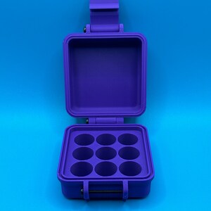 May include: A purple plastic storage box with a hinged lid and eight round compartments. The box is open and the compartments are empty.